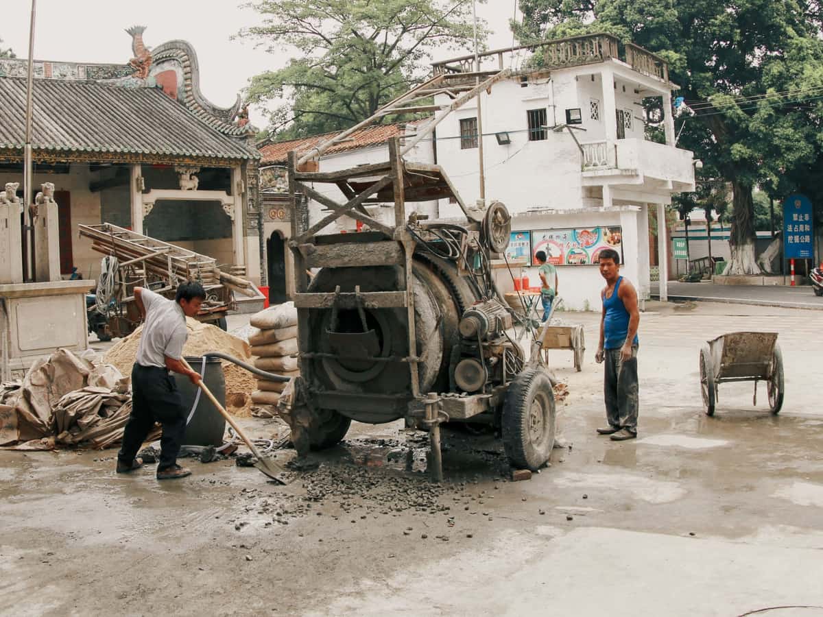 Two workers operating a cement mixer at an outdoor site