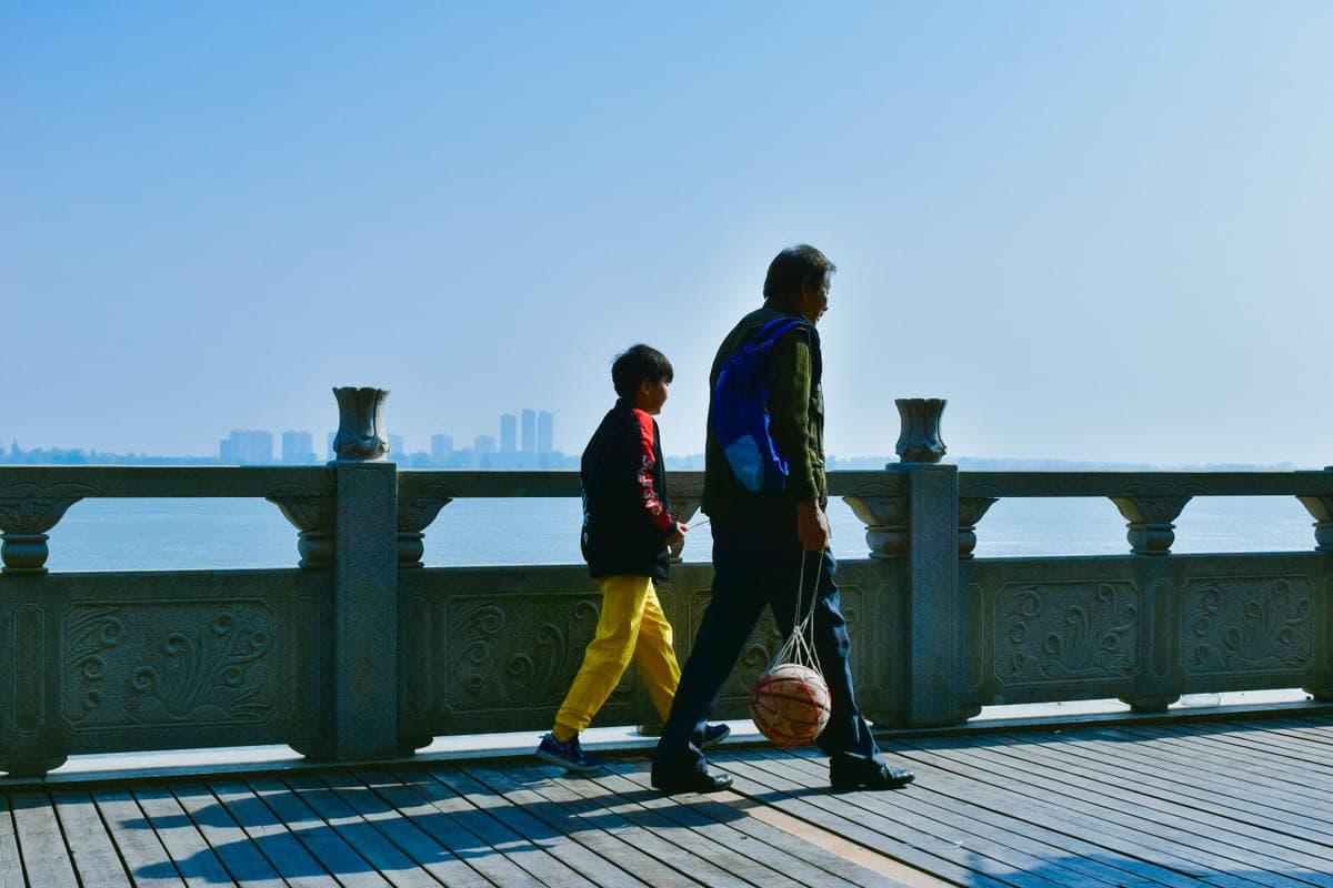 A father and son walking together carrying a basketball
