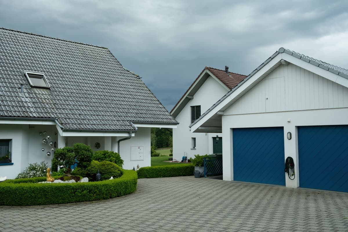 Suburban houses with garage doors and driveways under a cloudy sky