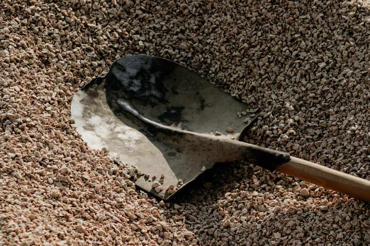A metal shovel lying on a pile of small gravel