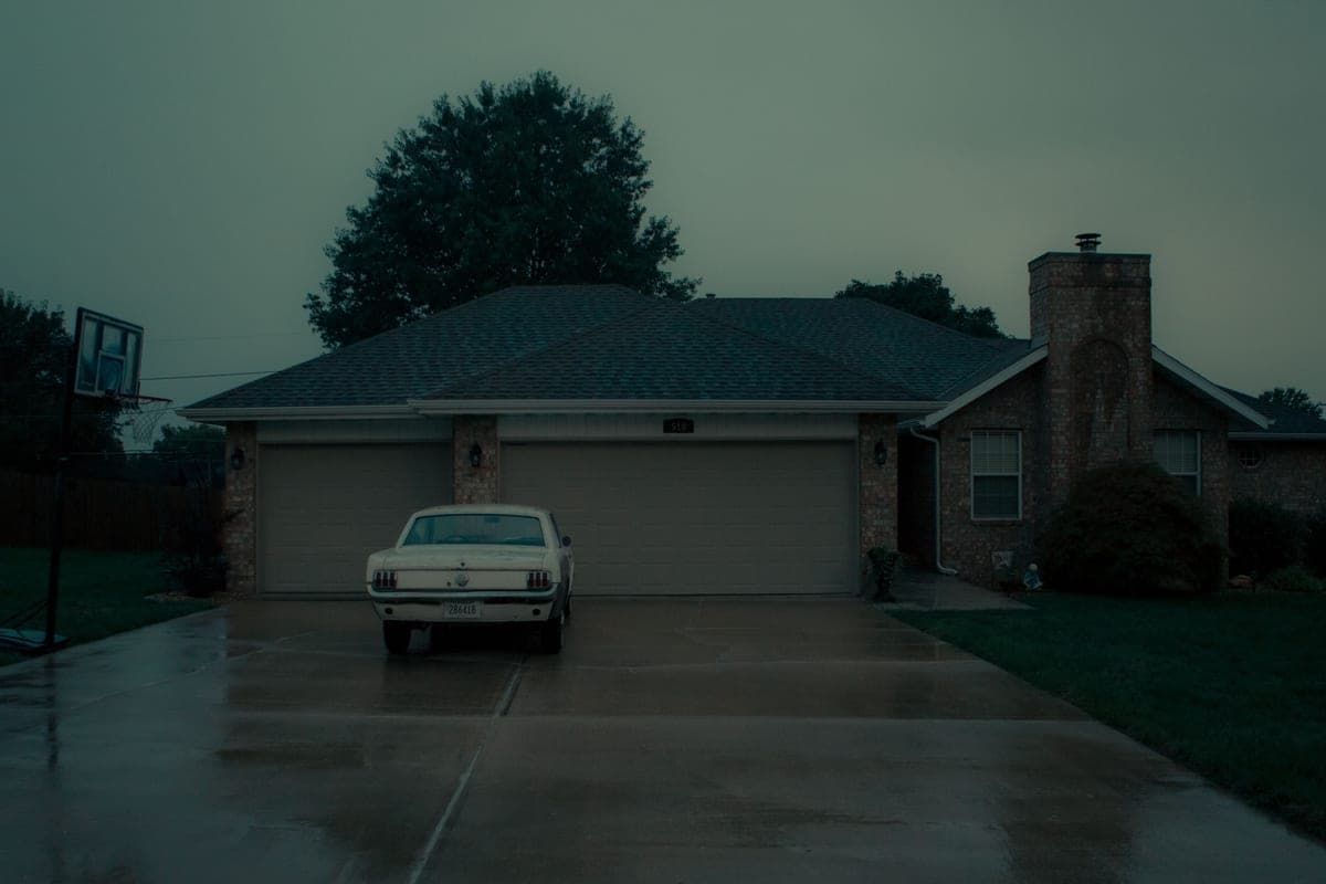A car parked on a wet suburban driveway on a rainy day