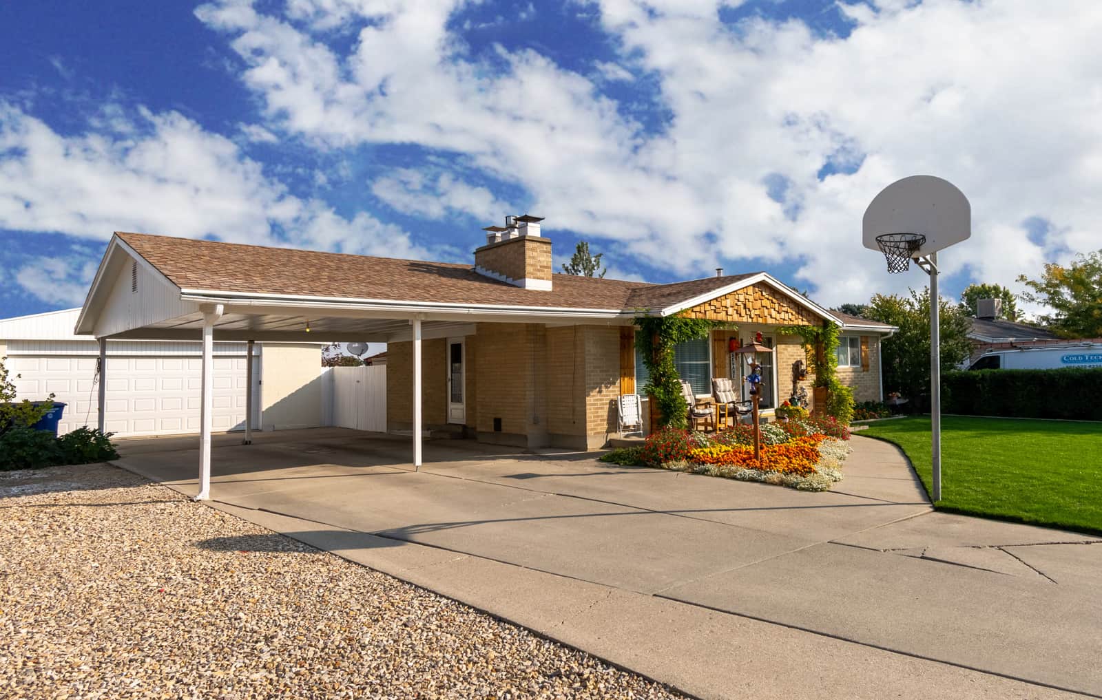 A suburban home with a basketball hoop at the top of the driveway beside the garage